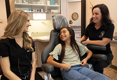 Team member talking to smiling patient in dental chair