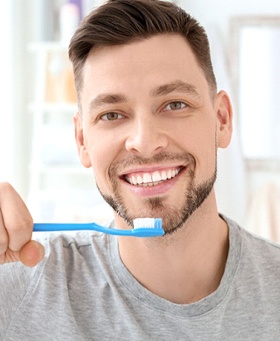 Man brushing his teeth in grey shirt