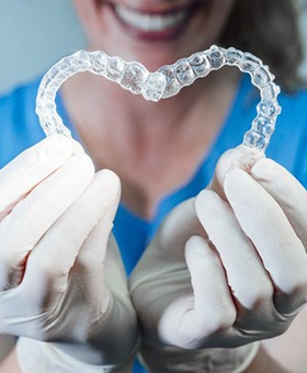 dental hygienist holding two clear aligners in the shape of a heart 