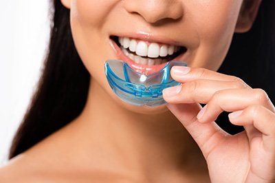Patient in Mangum holding a custom nightguard for bruxism