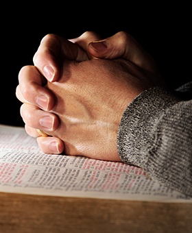 Person with clasped hands praying