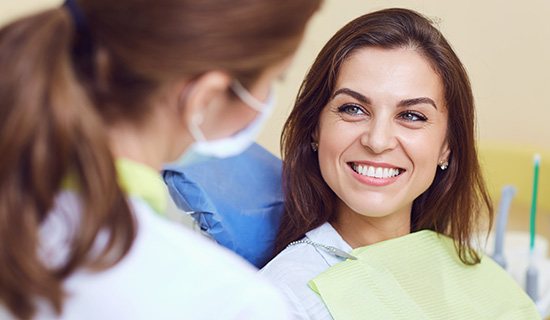 A smiling woman looking at her dentist