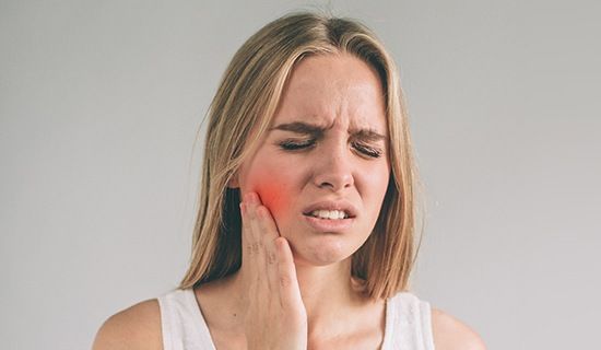 Woman in pain holding jaw