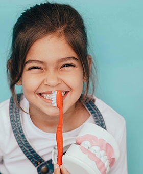 a child smiling while holding a toothbrush in Allen