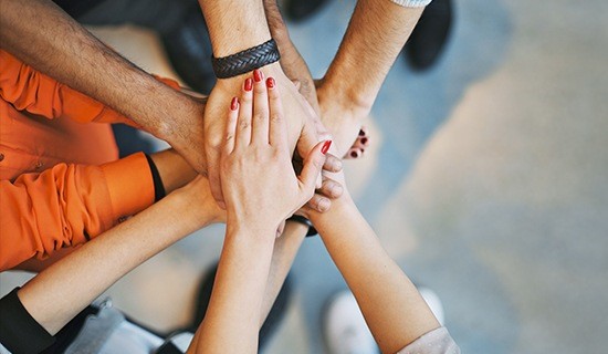 People in a circle stacking their hands together