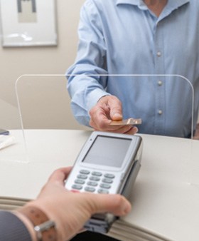 A man paying the cost of cosmetic dentistry