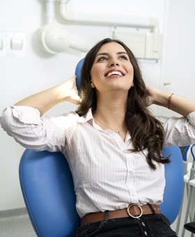 Woman smiling with hands behind her head at dental office