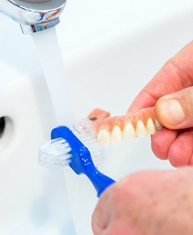 A person cleaning their dentures