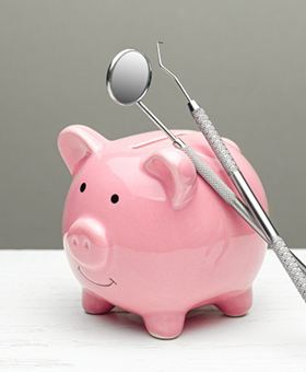 dental instruments leaning against a pink piggy bank  