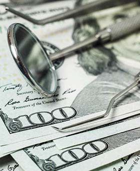 money and dental tools representing the cost of dental emergencies in Mangum
