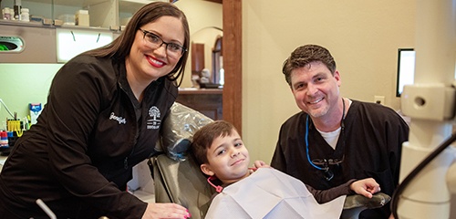 Dr. Lively and team member with young patient in exam room