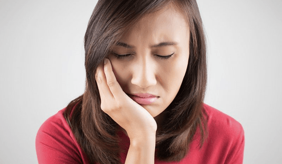 a woman experiencing pain due to a failed dental implant