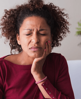 a woman experiencing pain from a failed dental implant 