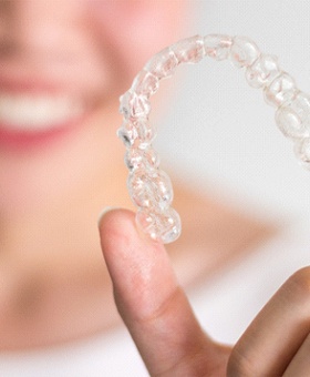 Woman holding up Invisalign clear aligner