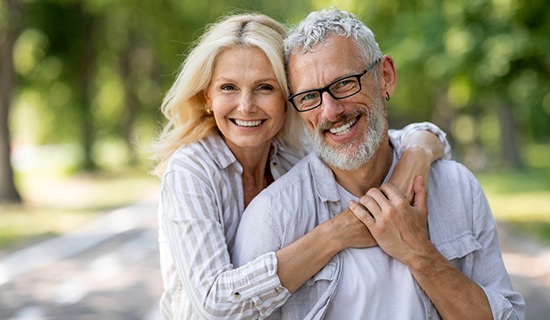 Middle-aged couple hugging and smiling after visiting MetLife dentist in Mangum