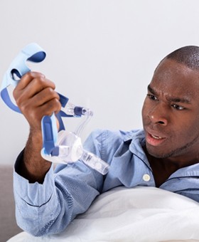 A young guy holding a CPAP mask