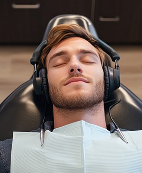 Relaxed young man in treatment chair, wearing headphones