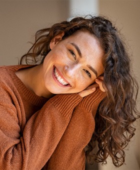 Woman in orange sweater leaning forward and smiling