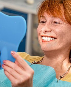 Older woman looking at her smile in the mirror