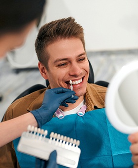 Dentist helping smiling patient select shade of veneers