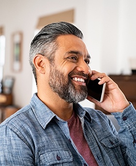 Man smiling while talking on phone at home