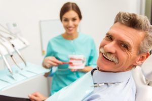 man with dentures in Mangum learning about denture adhesive from his dentist 