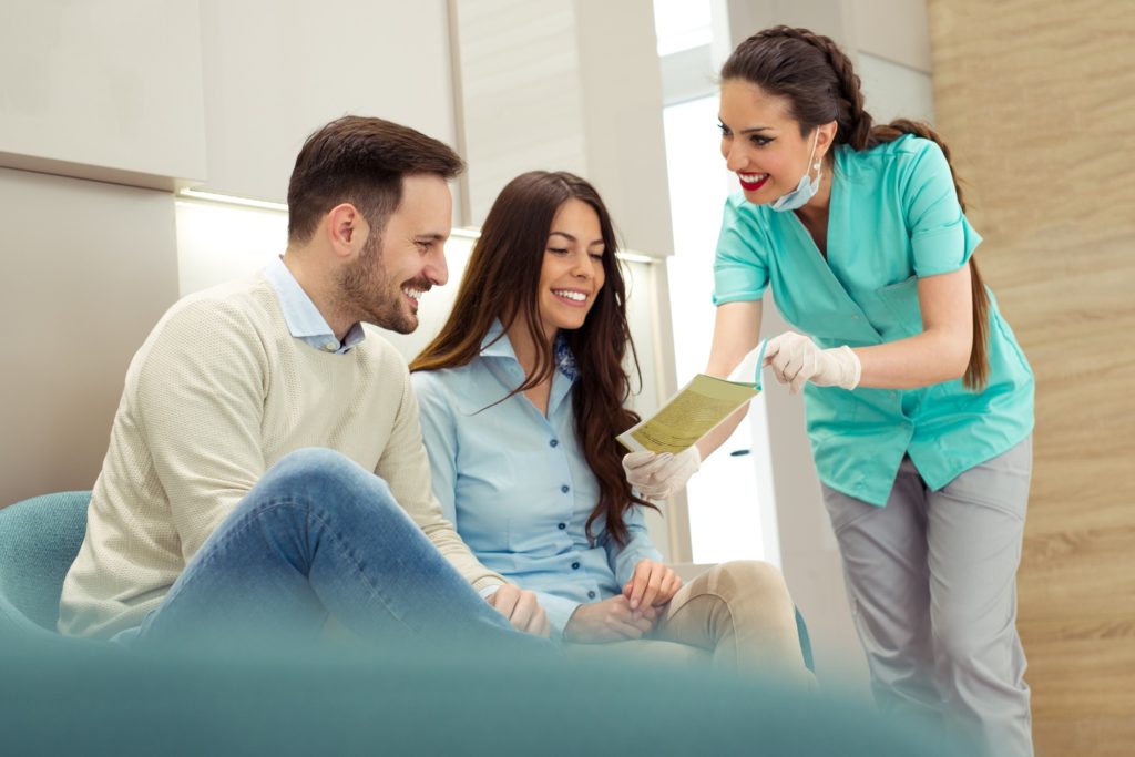 Dental assistant explaining dental insurance to smiling couple