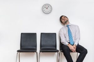 Man sitting in waiting room in front of a clock 