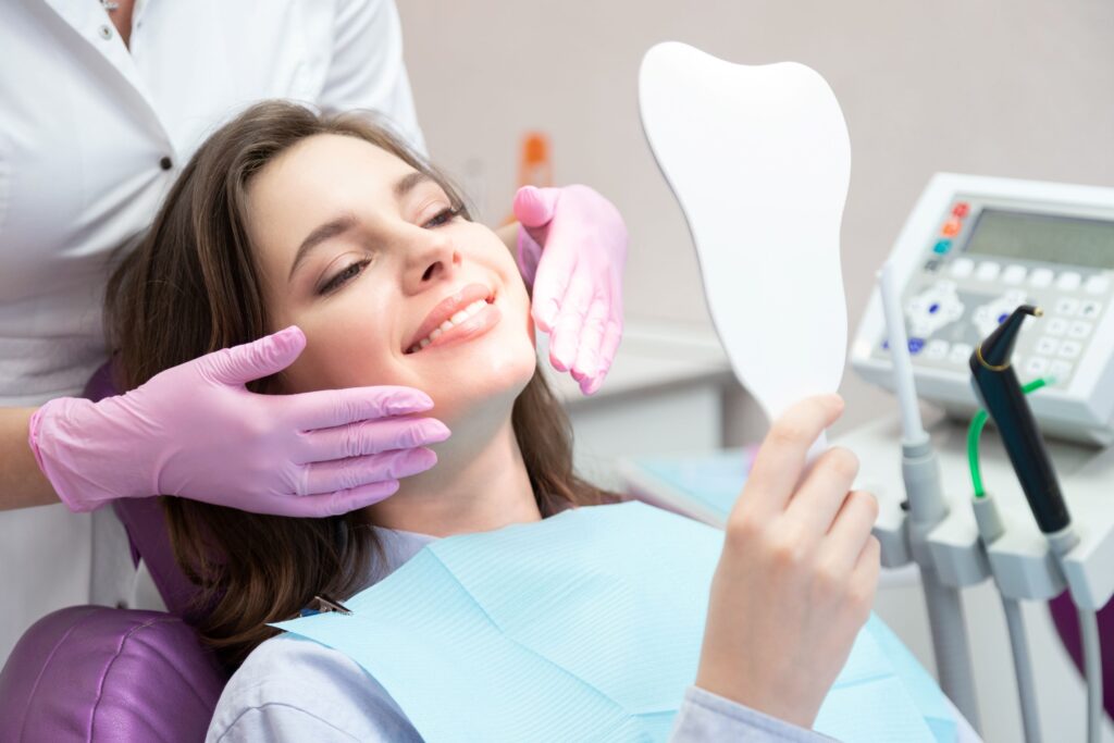 Woman in dental chair smiling with dentist's hands framing her face
