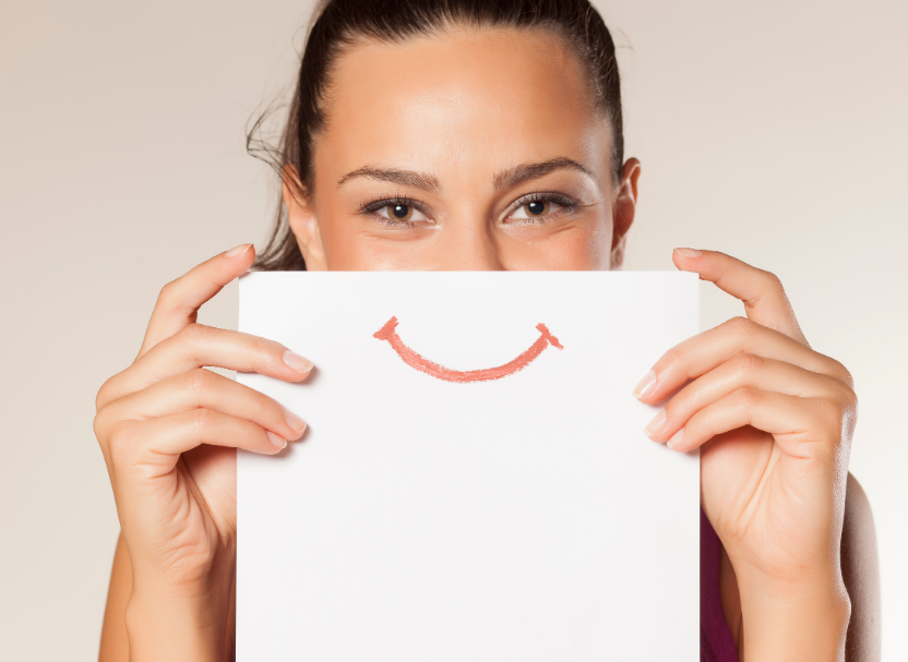 Woman holding paper with cartoon smile over mouth