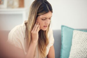 Woman holding side of face in pain.